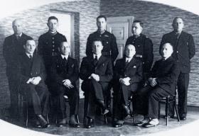Siedzi w pierwszym rzędzie w środku wśród innych oficerów Policji Państwowej. Zdjęcie z lat 30.