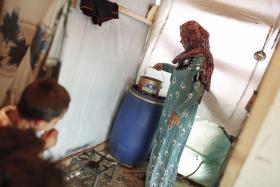 Jeden z syryjskich obozów w dolinie Bekaa w Libanie. Matka trójki dzieci gotuje wodę w namiocie, tymczasowym domu dla całej rodziny.