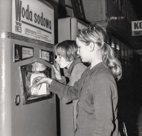 Automaty do wody sodowej, jakie pojawiły się w końcu lat 60., cieszyły się dużym zainteresowaniem, lecz nagminnie ginęły z nich szklanki. Wkrótce zdecydowano się mocować je na łańcuszkach. 

Na zdjęciu automat w hali na Koszykach, 1969 rok.