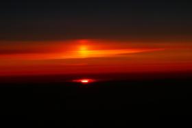 Supersłońce (to wyżej). Widok z samolotu nad Norwegią. Rozprzestrzenione w atmosferze kryształki lodu tworzą zwierciadło, w którym odbija się obraz zachodzącego Słońca. Taki fenomen jest widoczny dla obserwatorów znajdujących się ponad linią horyzontu.