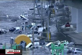 Kadr z telewizji NHK. Pokazuje samochody porwane przez falę tsunami.