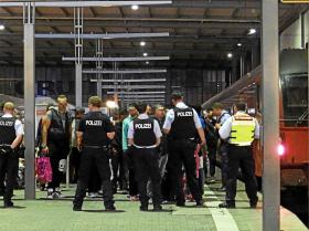 Uchodźcy eskortowani przez policję na dworcu kolejowym w Monachium.