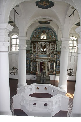 Wnętrze Wielkiej Synagogi we Włodawie. Na pierwszym planie bima, za nią bogato zdobiony aron ha-kodesz (szafa na zwoje Tory)
