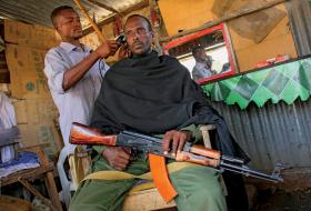 Żołnierz prorządowej brygady w Somalii nie odkłada broni nawet podczas strżyżenia.