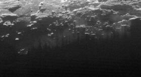 Na tym zdjęciu widać, jak zachodzące nad Plutonem Słońce oświetla przypowierzchniowe warstwy mgieł i oparów, które powstają z sublimującego azotowego lodu planety. Mgły pocięte są równoległymi cieniami pobliskich szczytów.