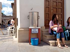 Pątnicy siadają przy wielkim stołówkowym baniaku wypełnionym wodą święconą – wodę można lać do butelek i bidonów za darmo.