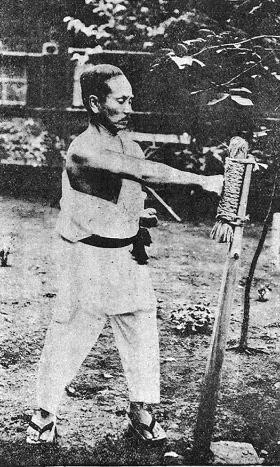 Gichin Funakoshi, założyciel stylu karate Shotokan, mistrz ciężkiej pracy, ćwiczący z przyrządem zwanym makiwara.