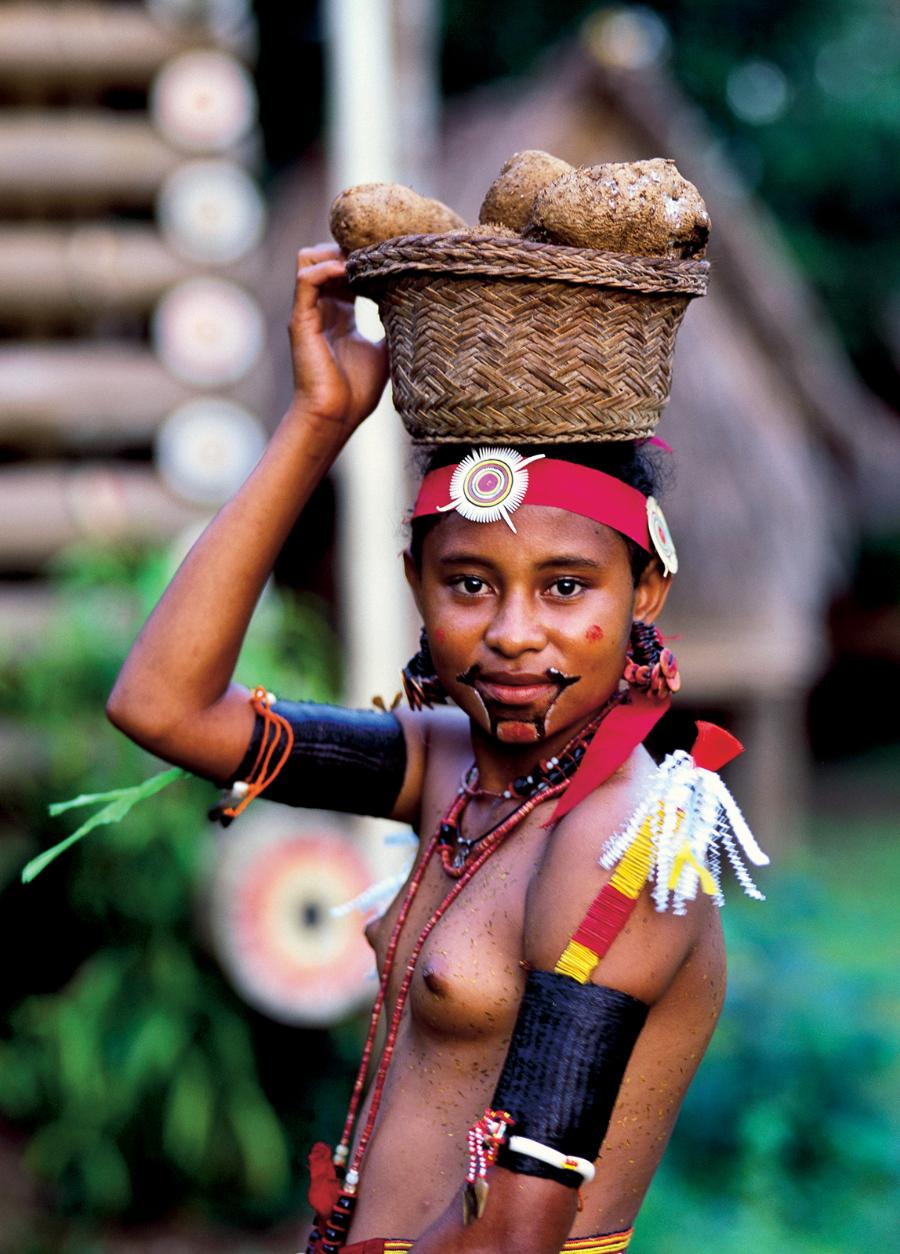 Współcześni mieszkańcy archipelagu przy tradycyjnych czynnościach. Kobieta niesie kosz z batatami.