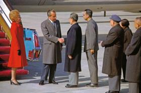 Na lotnisku w Pekinie Richard Nixon ściska dłoń Zhou Enlaia. Pierwsza dama Pat Nixon stoi po lewej, 21 lutego 1972 r.