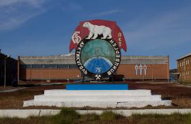 Tablica upamiętniająca 65-lecie firmy Trust Arktikugol odpowiedzialnej za wydobycie węgla, w tle Pałac Kultury.