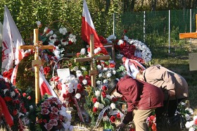 Rosjanki układają wiązankę kwiatów wśród wieńców.