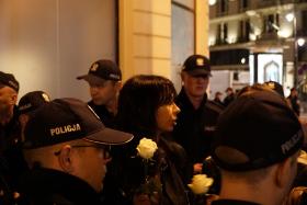 Cztery osoby otacza 18 policjantów.