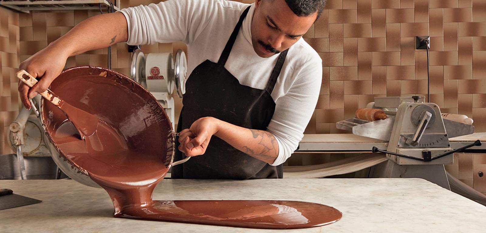 Płynna czekolada wylewana przez szefa produkcji na marmurowy stół.