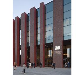 Siedziba NOSPR to zdecydowanie największy i najdroższy w realizacji finalista tegorocznej nagrody. Trochę przypomina rosyjską matrioszkę, czyli babę w babie. Prosty budynek o regularnych i czytelnych podziałach z dwoma wyraźnymi, ale nienachalnymi nawiązaniami do śląskiej tradycji: efektowną elewacją z cegieł oraz czerwonymi otworami okiennymi.