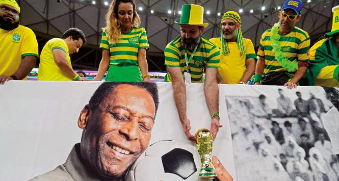 Kibice reprezentacji Brazylii z repliką pucharu mistrzostw świata nad zdjęciem Pelego.
