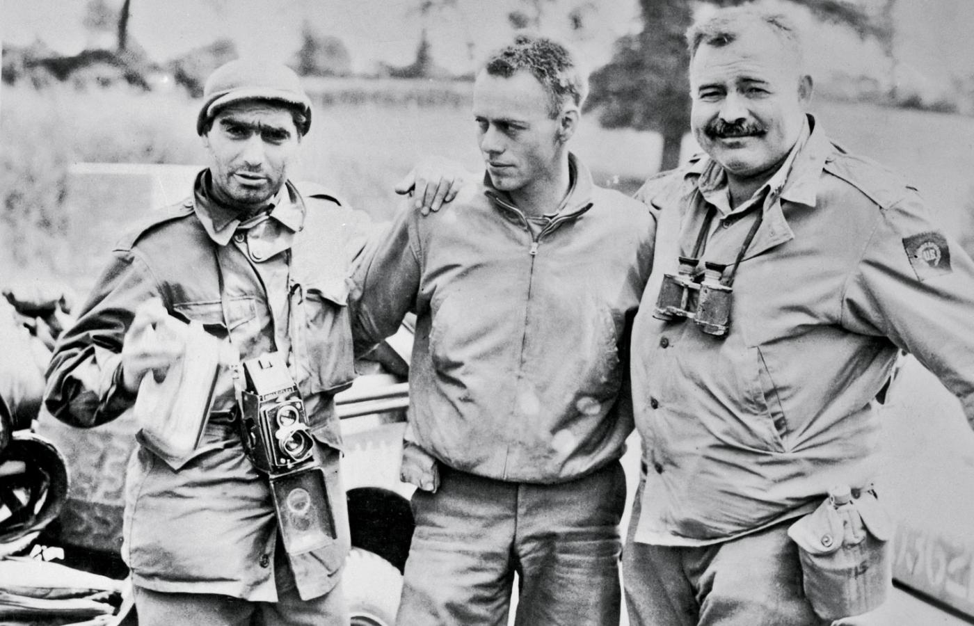 Robert Capa (z lewej), fotoreporter magazynu „ Life”, z Ernestem Hemingwayem (z prawej) i kierowcą stoją przy dżipie.