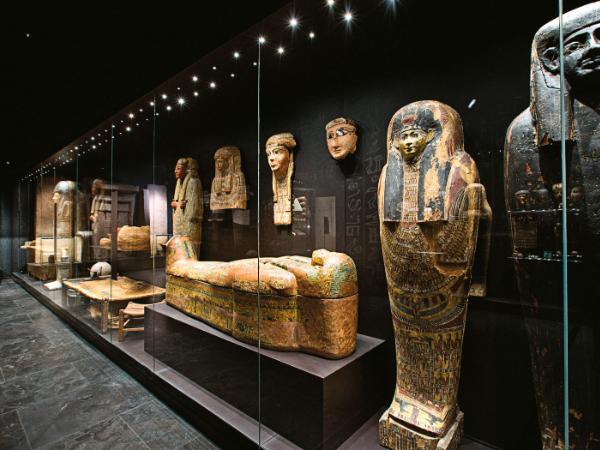 Zaciemniona sala z mumiami i innymi przedmiotami ze staroegipskich grobów.