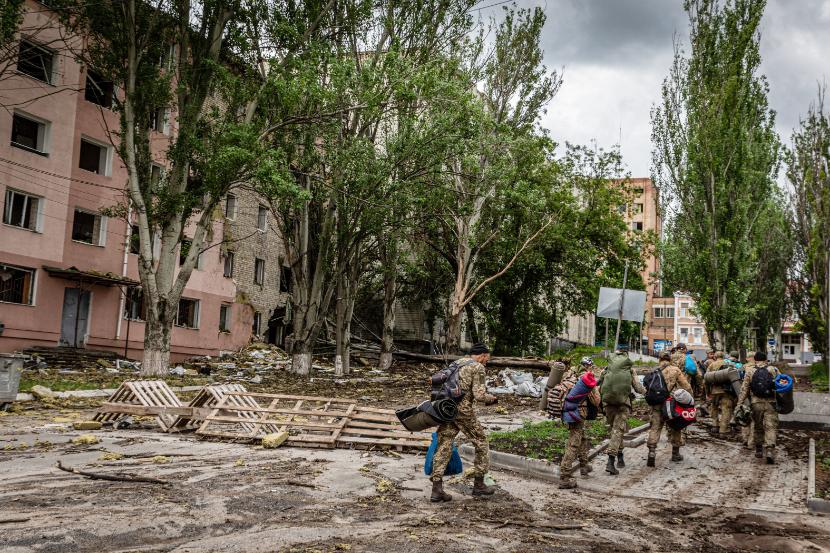 W obwodzie donieckim (Donbas) trwają zaciekłe walki między siłami ukraińskimi a rosyjskimi. Na zdjęciu: ukraińscy żołnierze przechodzą obok zniszczeń po rosyjskich nalotach w mieście Bachmut. 22 maja 2022 r.