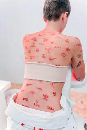 Logo słynnych firm odzieżowych wytatuowane na ciele performerki Leny Vackovej.