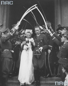 Po uroczystości państwo młodzi wychodzą już pod wspólnym nazwiskiem. Na zdjęciu Państwo Roman i Hanna Rożałowscy przechodzą wśród szpaleru kolegów oficerów z uniesionymi szablami. Kraków (?) 1939 r.
