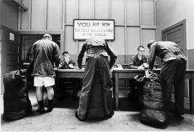 Poborowi podpisują dokumenty pod tablicą z napisem „Jesteś najlepiej ubranym żołnierzem na świecie”, Fort Jackson, 1972 r.