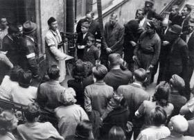 Odczytywanie komunikatu władz powstańczych na podwórzu kamienicy przy Moniuszki