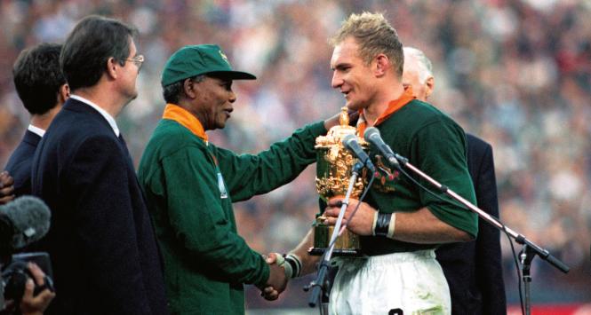 Francois Pienaar, kapitan Springboksów – drużyny RPA, po wygranym meczu z Nową Zelandią
odbiera trofeum z rąk Nelsona Mandeli, 1995 r.