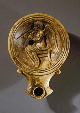 Grająca na podwójnych piszczałkach bogini Nike na rzymskiej lampce z terakoty.