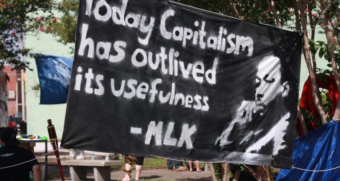 Baner przedstawia Martina Luthera Kinga i cytat: „Dzisiaj Kapitalizm przeżył swoją użyteczność”.