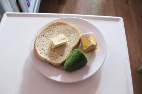 Polska: suchy chleb z masłem, ogórek i kawałek kiełbaski.