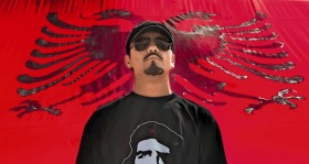 Albańczyk na tle flagi narodowej w Prisztinie.