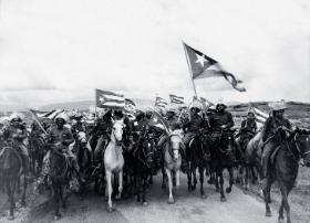 Kubański rewolucjonista Camilo Cienfuegos (z dużą flagą) na czele chłopskiego oddziału, 1959 r.