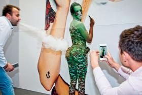 Jeden z wystawców na targach wyrobów tytoniowych postanowił pokryć hostessę barwami ochronnymi, ta fantazja przypadła niektórym gościom do gustu.