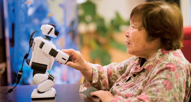 90-letnia pensjonariuszka hospicjum pod Tokio z robotem Parlo. Do połowy przyszłej dekady w Japonii będzie brakować prawie 400 tys. opiekunów. Lukę tę mają wypełnić inteligentne maszyny.