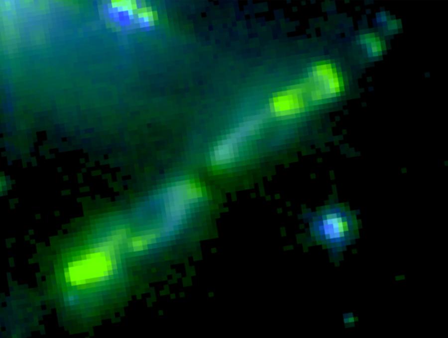 Rozproszona zielona poświata (tzw. zielone futrzaki) widziane przez Teleskop Kosmiczny Spitzera. Zdjęcie złożone z trzech filtrów: 3,6 μm (niebieski), 4,5 μm (zielony) i 8 μm (czerwony).
