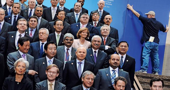 Robotnik podtrzymujacy dekoracje podczas spotkania G20 w siedzibie MFW w Waszyngtonie, kwiecień 2011 r. Obecna szefowa Funduszu Christine Lagarde w lewym dolnym rogu fotografi.