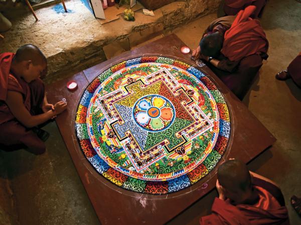 Sypanie mandali Mandala to motyw artystyczny w sztuce buddyjskiej; jej tworzenie, a następnie niszczenie jest uważane za rodzaj medytacji i ma duże znaczenie religijne. Polega na harmonijnym łączeniu kół i kwadratów, gdzie koło jest symbolem nieba, zewnętrzności i nieskończoności, a kwadrat wnętrza, tego co jest związane z człowiekiem i ziemią.