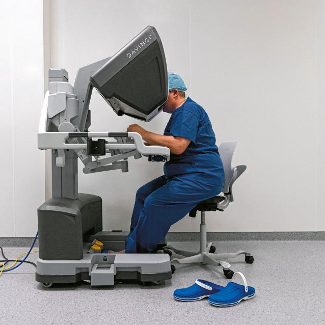 System da Vinci: chirurg siedzi przy konsoli, sterując ramionami robota.