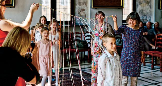 Ceremonia postrzyżyn-zaplecin. Sznureczki trzyma jedna z organizatorek uroczystości Elżbieta Rutkowska. Za nią prof. Ewa Graczyk, mistrzyni ceremonii.