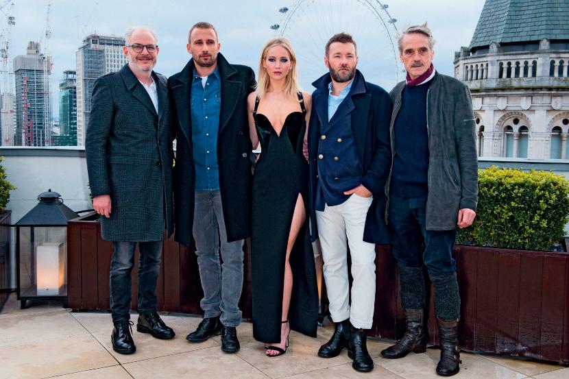 Jennifer Lawrence jako jedyna występuje w skąpym stroju, podczas gdy otaczający ją mężczyźni mają na sobie ciepłe płaszcze