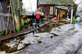 Gospodarz układa drogę do domu z desek zawieszonych na oponach samochodowych.