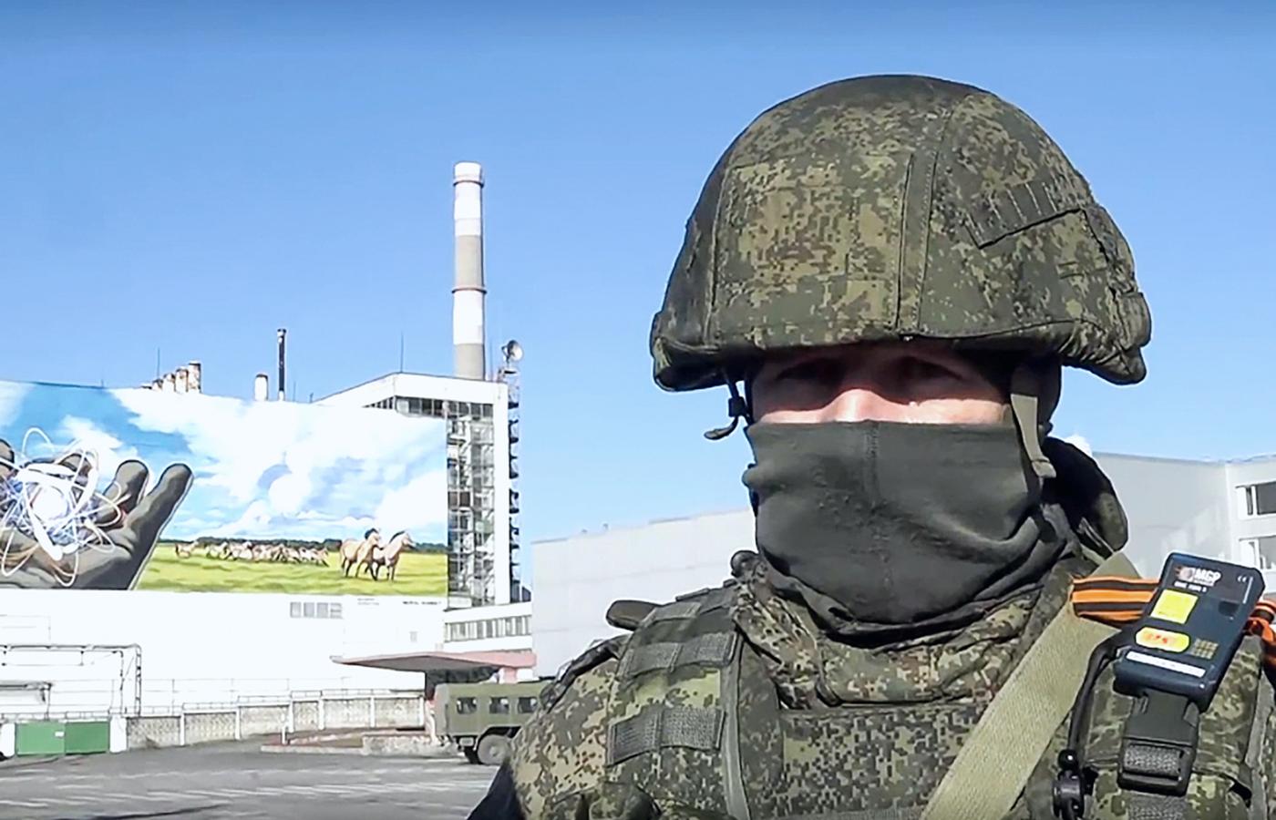 Rosyjski żołnierz na tle elektrowni w Czarnobylu.