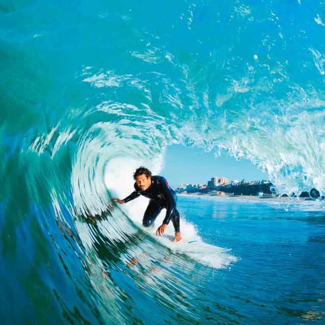 Surfer w „­beczce” utworzonej przez falę.