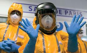 Francuzi prezentujący kombinezon wykorzystywany przy opiece nad zakażonymi ebolą.