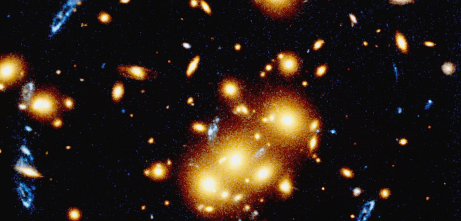 Gromada galaktyk oznaczona symbolem 0024+1654, leżąca w odległości 5 mld l.ś. od nas. Działa jak silna soczewka grawitacyjna powiększająca dwa razy dalej położoną galaktykę widoczną tu pod postacią niebieskich plam.