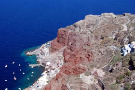 Wulkaniczna wyspa Santorini z czarnymi plażami, półkolistymi granatowymi dachami domów, niewielkimi zasobami słodkiej wody.