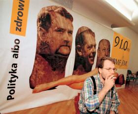 Szef RMF Stanisław Tyczyński na tle kontrowersyjnego billboardu reklamowego.