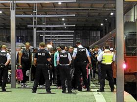 Uchodźcy eskortowani przez policję na dworcu kolejowym w Monachium.