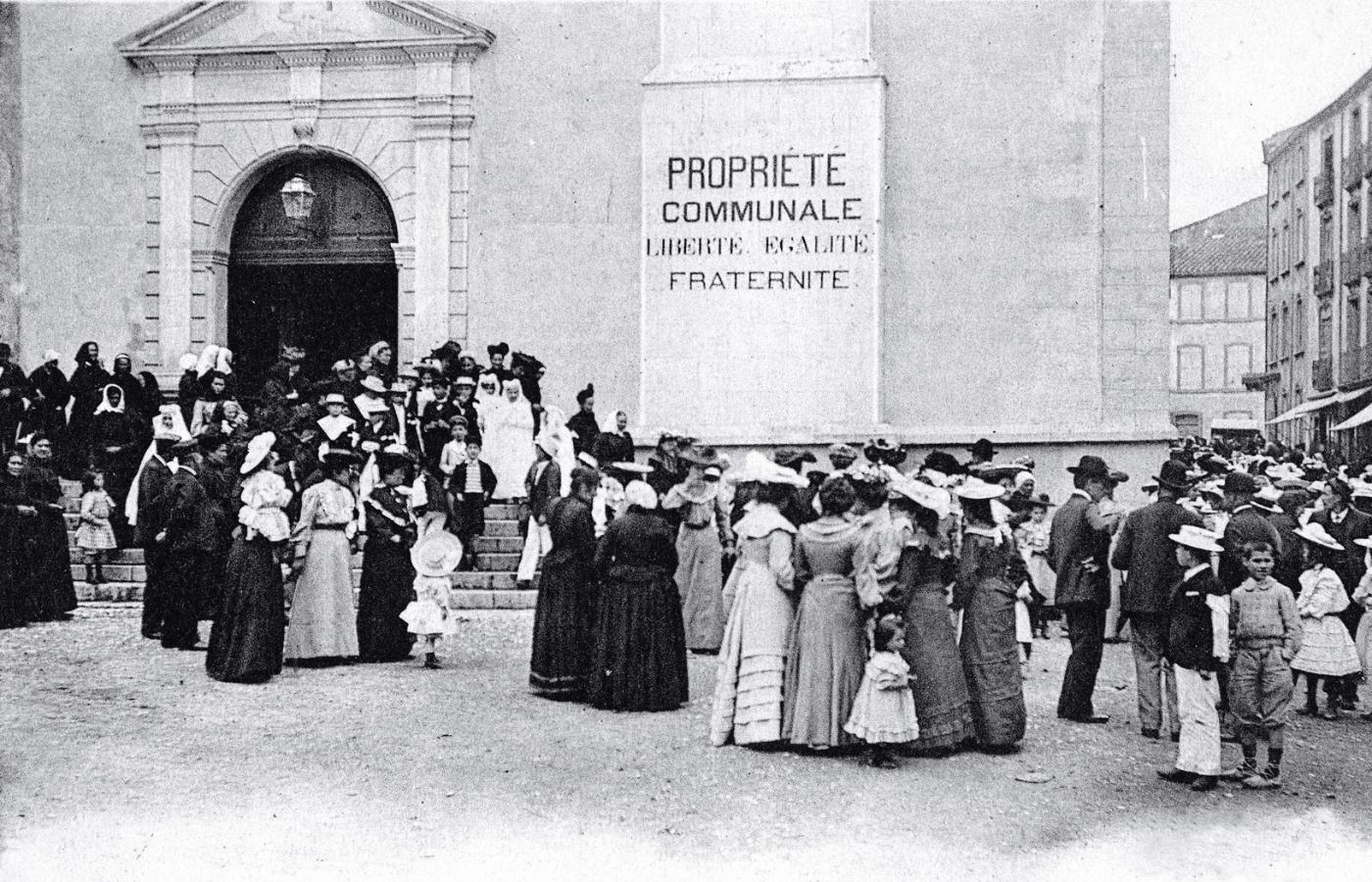 „Własność komunalna – Wolność, Równość, Braterstwo”, napis na fasadzie kościoła w Sigean (Oksytania); pocztówka z 1905 r.