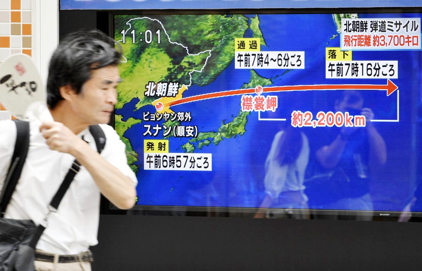 Przechodzień w Tokio na tle ekranu, na którym pokazano atak ze strony Korei Północnej.